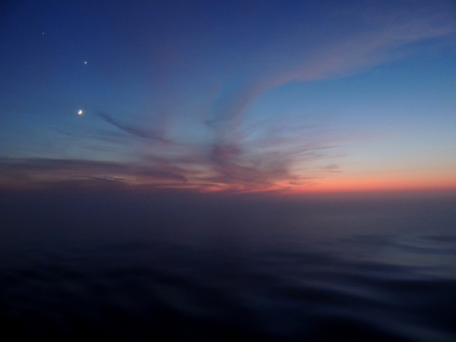 Ocean and atmosphere merge together at sunset while moon, Jupiter and Venusare seen above the horizon