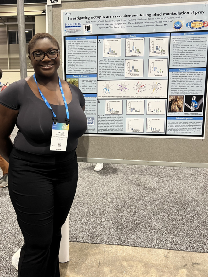 In an exhibit hall, Halia poses next to a her scientific poster "Investigating octopus arm recruitment during blind manipulation of prey."