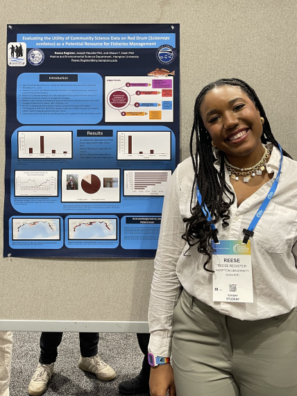 In an exhibit hall, Reese poses next to a her scientific poster "Evaluating the utility of community science data on red drum (sciaenops ocellatus) as a potential resource for fisheries management."