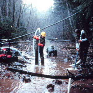 Three men in the river operate the pump