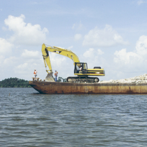 Barge and crane preparing to unload rock