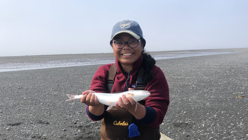 Brianne Visaya, a 2018 Hollings scholar, holds a Dolly Varden caught during a beach seine at a fieldwork site. She interned at the Kasitsna Bay Lab in Kachemak Bay, Alaska, in the summer of 2019.