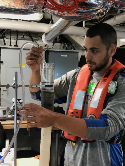Anthony Lima, graduate student at University of Texas Rio Grande Valley, removes water overlaying a core of sediment collected from the bottom of the Gulf of Maine. The sediment subsample is processed and the algal cysts are collected and preserved for counting back in the lab.