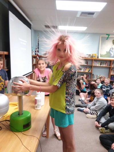 A student learns about static electricity through the use of a Van de Graaff generator.