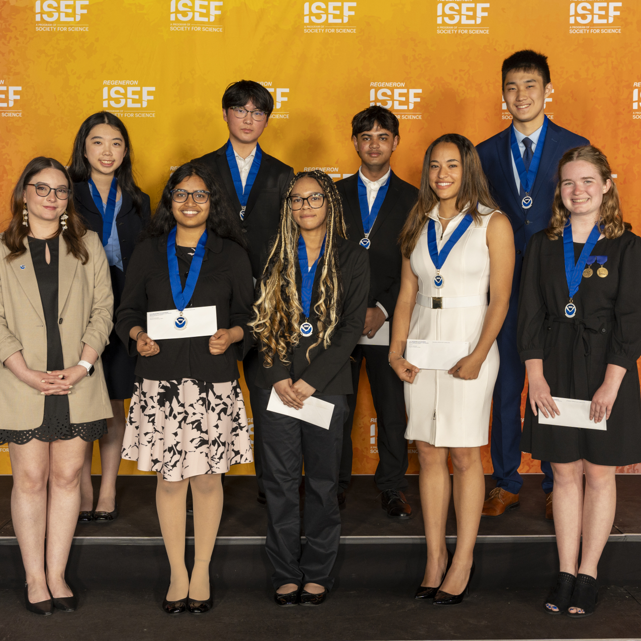 A group of nine young adults pose for a group photo in front of a backdrop with the ISEF logo.